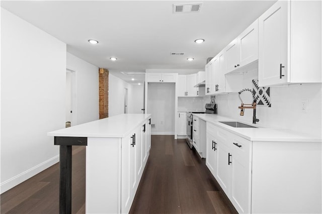 kitchen featuring a kitchen island, dark hardwood / wood-style floors, white cabinetry, sink, and electric range