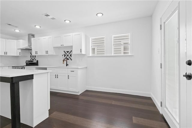 kitchen with stainless steel range with electric stovetop, wall chimney range hood, white cabinetry, and dark wood-type flooring