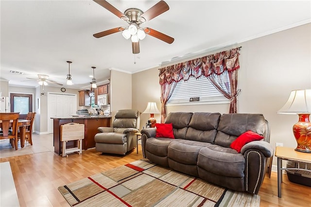 living room featuring ceiling fan, crown molding, and light hardwood / wood-style flooring