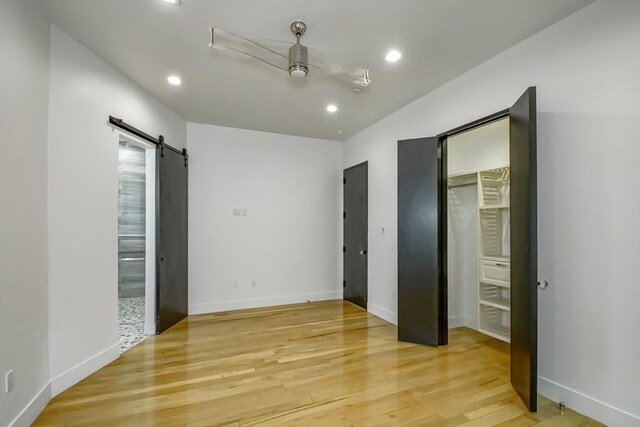 4317 Anthony St, Metairie, LA 70001 - unfurnished bedroom with a barn door, light wood-style flooring, recessed lighting, baseboards, and a ceiling fan