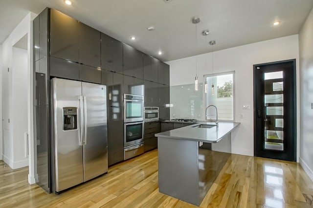 4317 Anthony St, Metairie, LA 70001 - kitchen with appliances with stainless steel finishes, a sink, a peninsula, light wood finished floors, and a warming drawer
