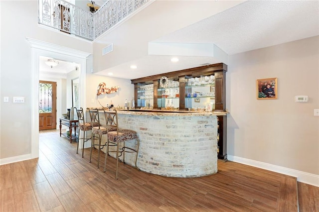 bar with a towering ceiling and hardwood / wood-style flooring