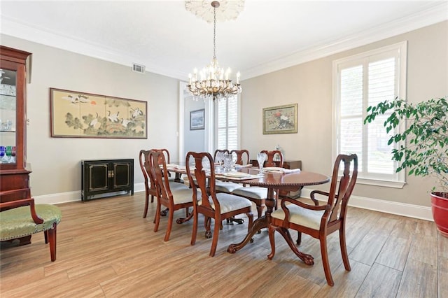 dining space featuring a notable chandelier, light hardwood / wood-style flooring, and crown molding