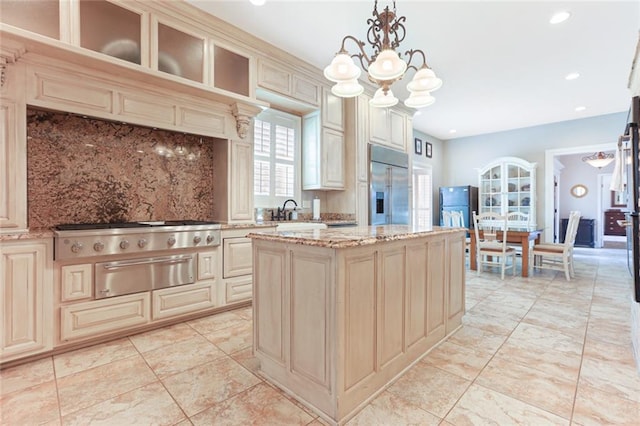 kitchen with pendant lighting, a chandelier, a center island, cream cabinetry, and stainless steel appliances