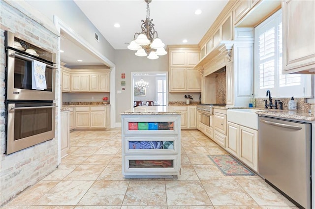 kitchen featuring sink, decorative light fixtures, stainless steel appliances, a notable chandelier, and light stone countertops