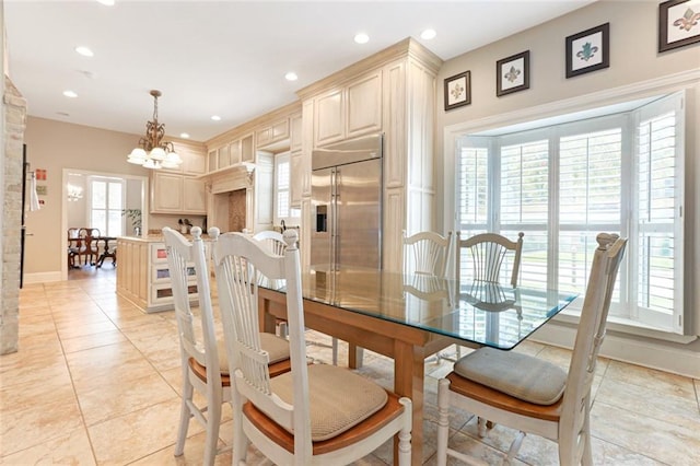 tiled dining room featuring an inviting chandelier and plenty of natural light