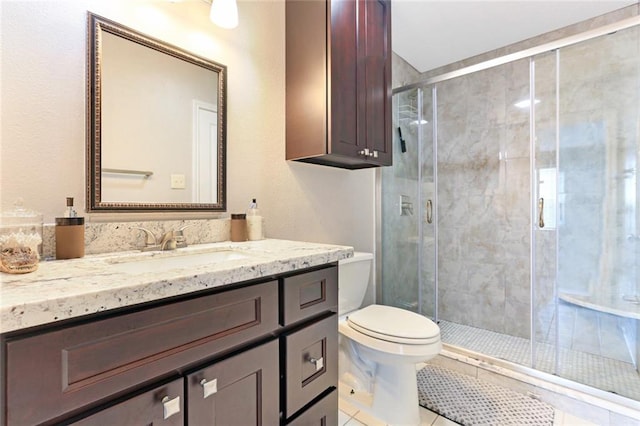 bathroom with tile patterned flooring, a shower with door, vanity, and toilet