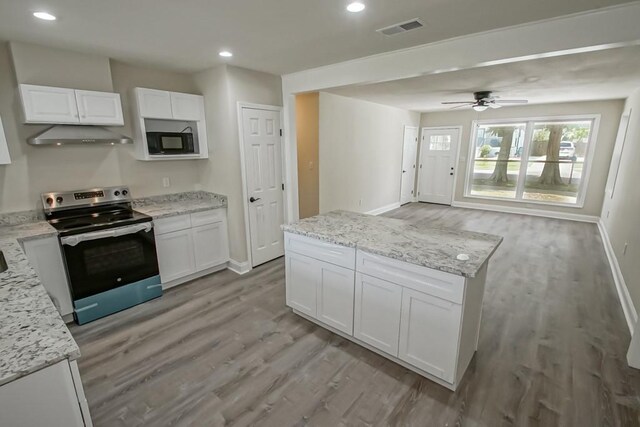 kitchen with black microwave, ceiling fan, stainless steel range with electric cooktop, white cabinets, and exhaust hood