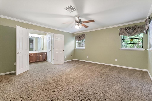 unfurnished bedroom with carpet, ornamental molding, ceiling fan, multiple windows, and connected bathroom