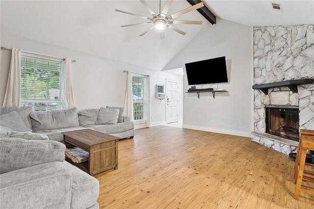 living room featuring ceiling fan, light wood-type flooring, plenty of natural light, and beam ceiling