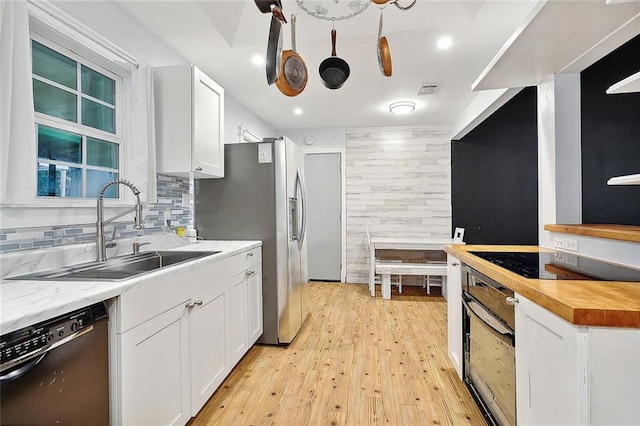 kitchen featuring light hardwood / wood-style flooring, white cabinetry, sink, black appliances, and wooden counters