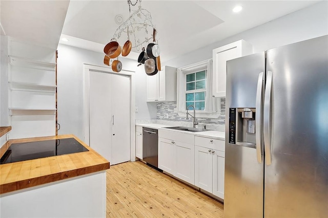 kitchen featuring light wood-type flooring, wood counters, decorative backsplash, white cabinetry, and stainless steel appliances