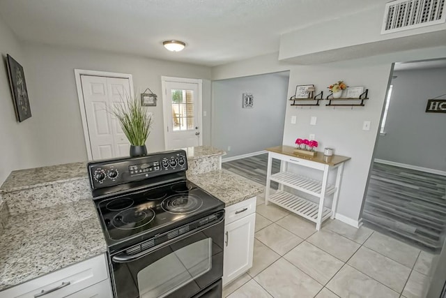 kitchen with black electric range, white cabinets, and light wood-type flooring