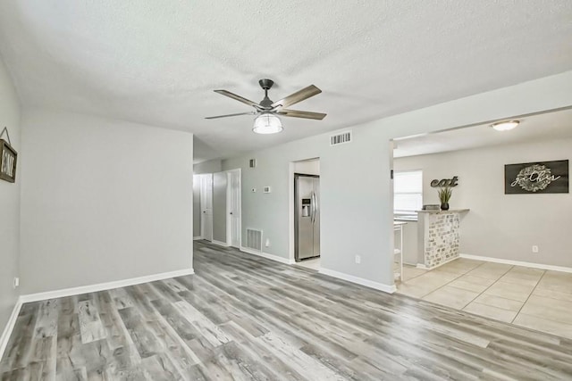 interior space featuring a textured ceiling, light hardwood / wood-style flooring, and ceiling fan