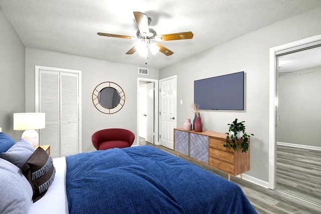 bedroom with multiple closets, ceiling fan, and wood-type flooring