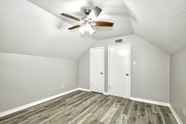 bonus room with hardwood / wood-style flooring, lofted ceiling, a textured ceiling, and ceiling fan