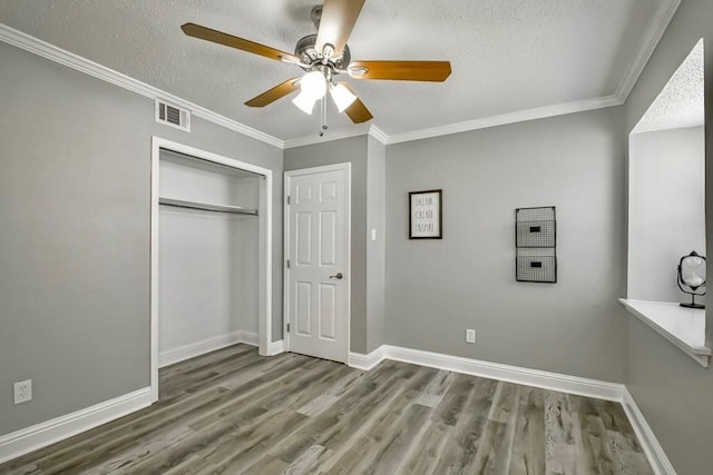 unfurnished bedroom with ornamental molding, ceiling fan, hardwood / wood-style floors, and a closet