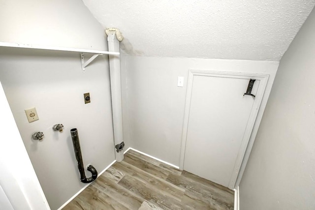 laundry area featuring electric dryer hookup, a textured ceiling, and light hardwood / wood-style floors