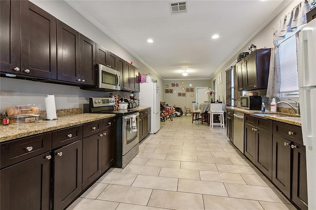 kitchen with appliances with stainless steel finishes, sink, light stone countertops, crown molding, and dark brown cabinetry