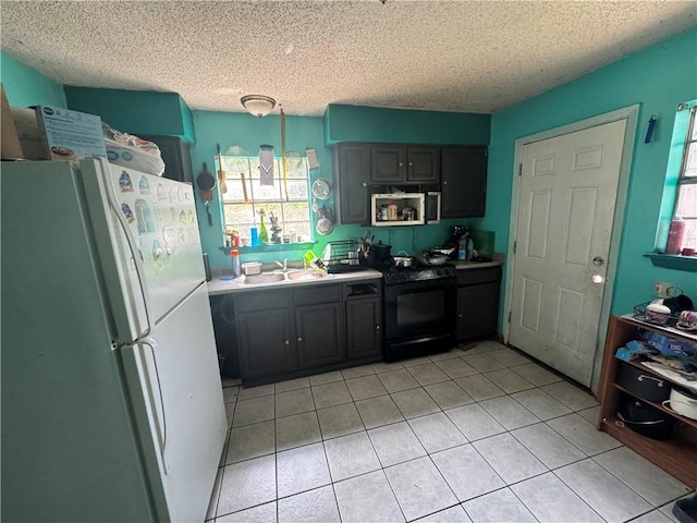 kitchen featuring white refrigerator, sink, black stove, a textured ceiling, and light tile patterned flooring