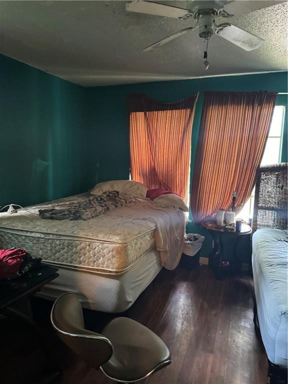 bedroom with a textured ceiling, ceiling fan, and wood-type flooring