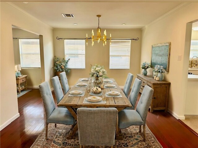 dining space featuring dark wood-type flooring, ornamental molding, and a chandelier