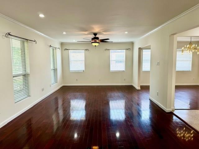 unfurnished room featuring ceiling fan with notable chandelier, dark wood-type flooring, and ornamental molding