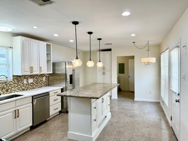 kitchen with sink, tasteful backsplash, a kitchen island, stainless steel appliances, and white cabinets