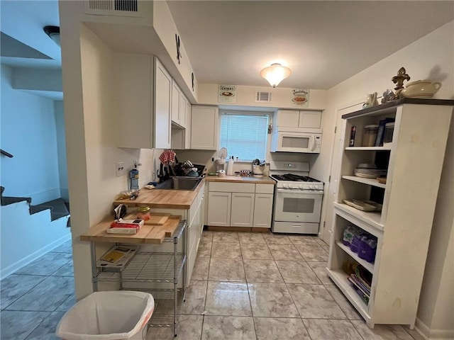 kitchen featuring white cabinetry, light tile patterned floors, wooden counters, and white appliances