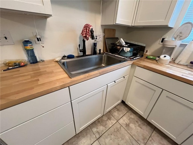 kitchen featuring white cabinetry, sink, and butcher block countertops