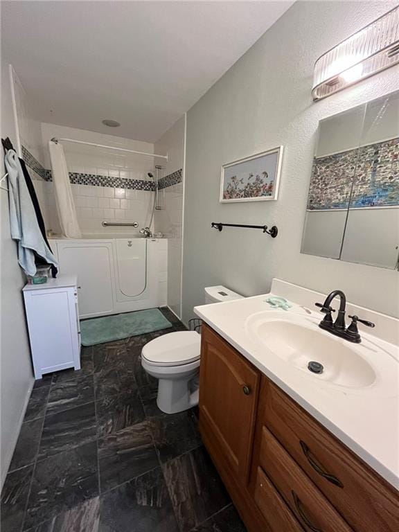 bathroom with vanity, toilet, and tiled shower