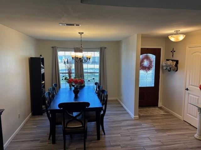 dining area with hardwood / wood-style floors and an inviting chandelier