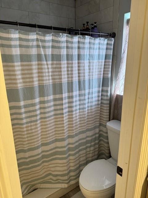 bathroom with a shower with curtain and toilet