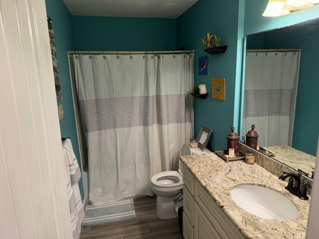 bathroom with hardwood / wood-style floors, vanity, toilet, and a shower with curtain