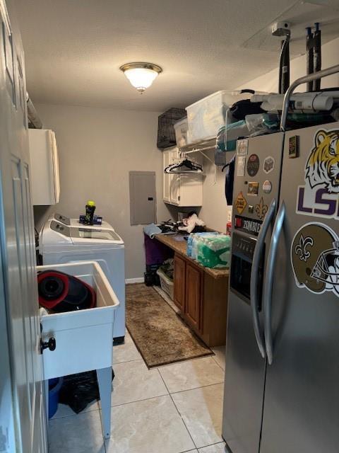 laundry room featuring cabinets, light tile patterned floors, washing machine and dryer, and electric panel