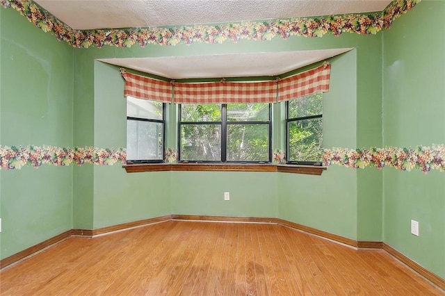 spare room featuring light hardwood / wood-style flooring and a textured ceiling