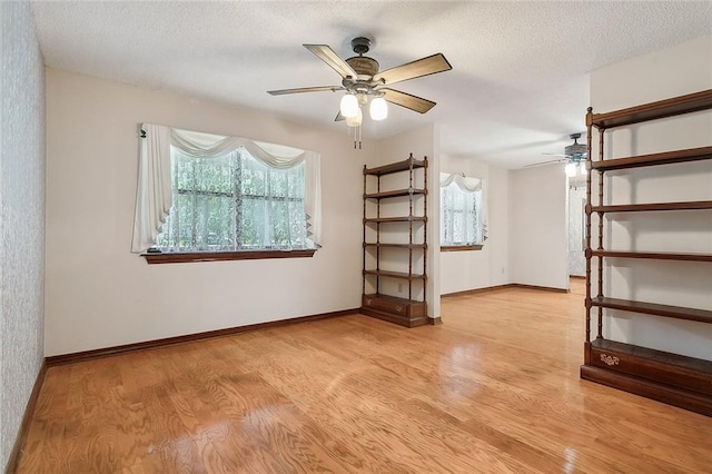 spare room with a textured ceiling, light wood-type flooring, and ceiling fan