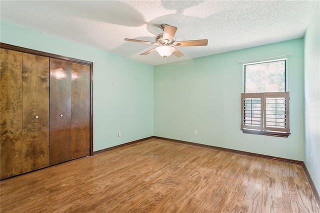 unfurnished bedroom featuring ceiling fan, a textured ceiling, light hardwood / wood-style flooring, and a closet