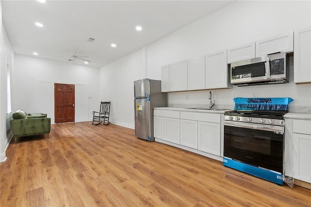 kitchen with light countertops, stainless steel appliances, a sink, light wood-style floors, and ceiling fan