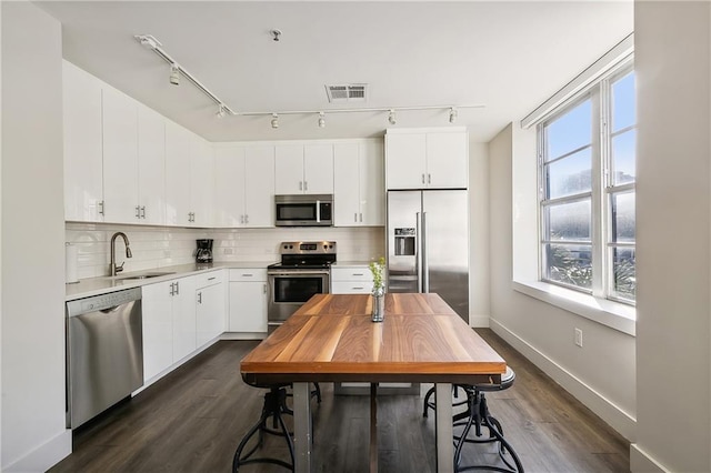 kitchen with appliances with stainless steel finishes, sink, dark hardwood / wood-style flooring, and white cabinets