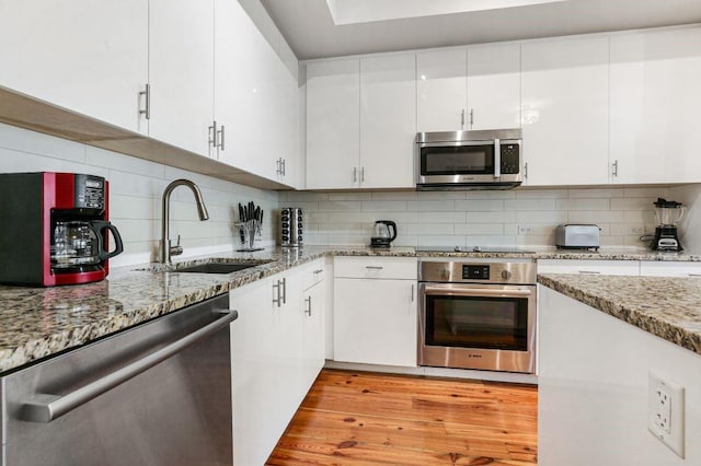 kitchen with backsplash, white cabinetry, appliances with stainless steel finishes, and sink