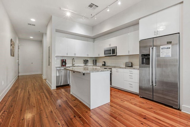 kitchen featuring a center island, tasteful backsplash, white cabinetry, light hardwood / wood-style flooring, and appliances with stainless steel finishes