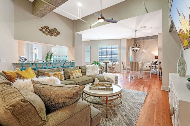 living room with a high ceiling, ceiling fan, and light hardwood / wood-style flooring