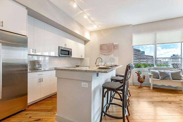 kitchen with white cabinets, appliances with stainless steel finishes, and light wood-type flooring