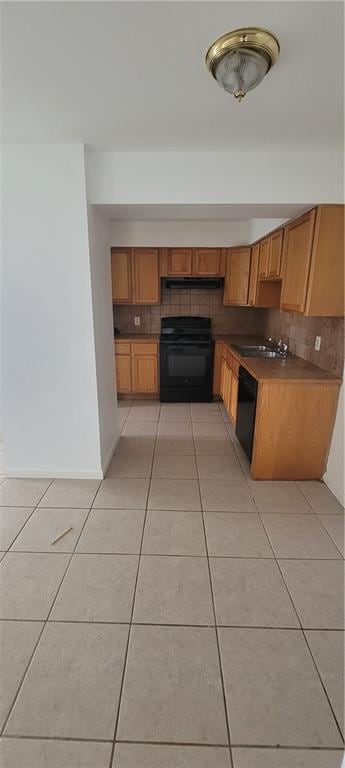 kitchen featuring stove, backsplash, sink, black dishwasher, and light tile patterned flooring