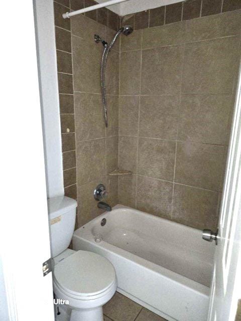 bathroom with tile patterned floors, tiled shower / bath, and toilet