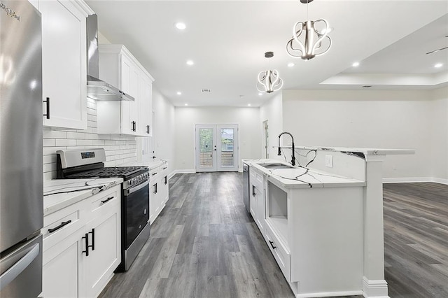 kitchen featuring white cabinetry, wood-type flooring, wall chimney exhaust hood, light stone counters, and appliances with stainless steel finishes