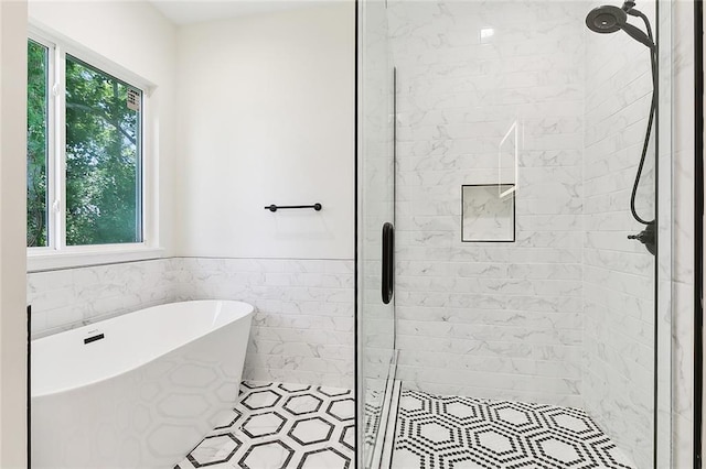 bathroom with tile patterned floors, separate shower and tub, and tile walls