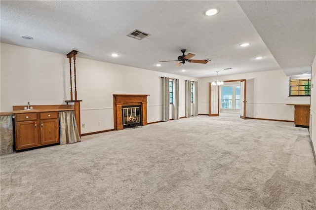 unfurnished living room with sink, a textured ceiling, ceiling fan, and light colored carpet