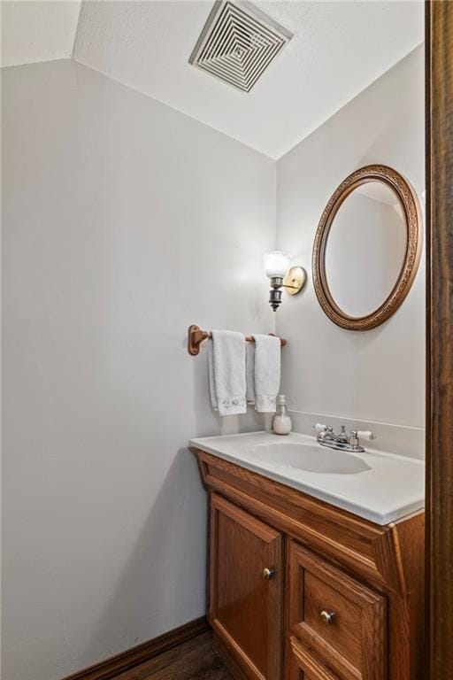 bathroom featuring vanity, lofted ceiling, and hardwood / wood-style flooring